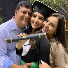 a man and woman pose for a photo while holding a graduation cap and diploma in front of them