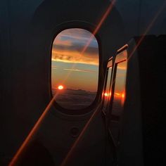 the sun is setting over the ocean as seen through an airplane's porthole window