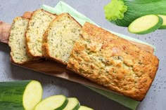 sliced zucchini bread sitting on top of a cutting board next to cucumbers