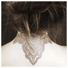 the back of a woman's neck with an intricate tattoo design on her chest