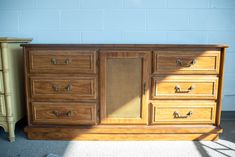 an old dresser is sitting next to a green chair