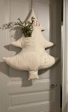 a christmas tree shaped pillow hanging on the front door with an evergreen branch in it