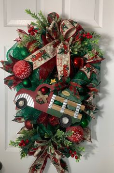 a christmas wreath on the front door decorated with ornaments and ribbons, including an old firetruck