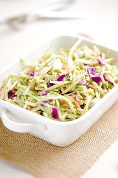 a white dish filled with coleslaw on top of a table