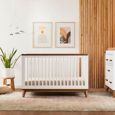 a white crib in the corner of a room with wood paneling on the walls