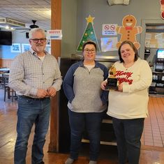 three people standing next to each other holding an award