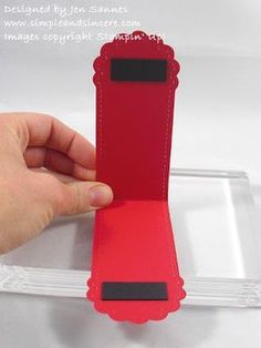 a hand is holding an empty red card holder in front of a clear box with black trim