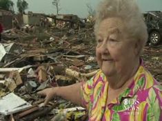 an older woman standing in front of a pile of debris