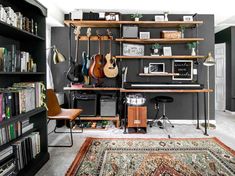 a room filled with lots of guitars and bookshelves on top of shelves next to a rug