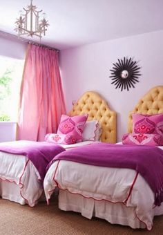 two beds in a room with pink walls and curtains