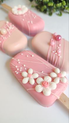 three pink and white decorated pops sitting on top of a table