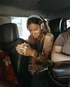 two women sit in the back seat of a car and look at their cell phones