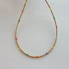 Add a pop of color to your outfit with this stunning Colorful Rainbow Small Glass Crystal Beaded Necklace. The mix of gold gem seed beads delicate creates a beautiful boho look that is both dainty and minimal. This piece of stone jewelry is the perfect gift for her, adding a touch of whimsy and elegance to any wardrobe. Handcrafted with care, this necklace is sure to become a favorite in your collection. Adjustable Multicolor Necklace With Gold Beads, Gold Beaded Chain Metal Necklaces, Gold Metal Beaded Chain Necklace, Gold Jewelry With Beaded Metal Chain, Gold Jewelry With Beaded Chain, Bohemian Gold Crystal Necklace With Spacer Beads, Gold Necklaces With Metal Beads, Gold Crystal Necklaces With Beaded Chain And Round Beads, Gold Crystal Necklaces With Beaded Chain