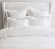 a bed with white sheets and pillows on it