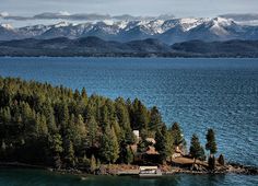 an island in the middle of water with mountains in the background