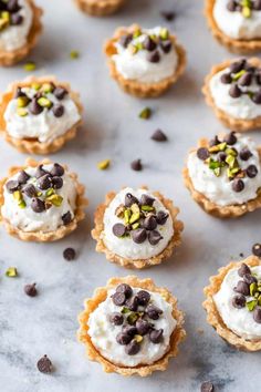 mini chocolate chip cookies topped with whipped cream and pistachio chips on a marble surface