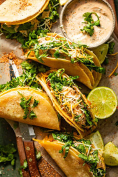 Cheesy Gordita Crunch tacos on a cutting board with spicy ranch sauce in a bowl and cut limes laying about. This homemade recipe that takes it up a notch.