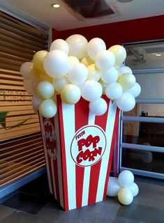 a popcorn box filled with white balloons sitting on top of a floor