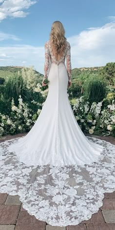 the back of a woman's wedding dress in front of flowers