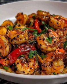 a white bowl filled with cooked shrimp and veggies on top of a table