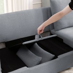 a person is opening up a couch with their hand on the seat and pulling it out