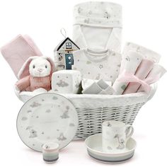 a white basket filled with baby items on top of a table next to a cup and saucer