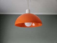 an orange lamp hanging from the ceiling in a room with gray walls and flooring