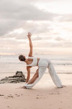 a woman is doing yoga on the beach