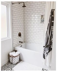 a white bath tub sitting next to a window in a bathroom with black and white tile