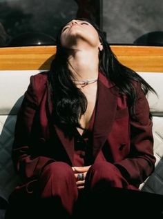 a woman sitting on top of a white couch next to a window with her eyes closed