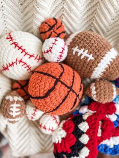 crocheted sports balls are arranged on a white knitted blanket with red, white and blue yarns