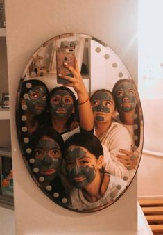 a group of people with painted faces taking a selfie in front of a mirror