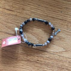 a beaded bracelet with black and white beads on a wooden table next to a price tag