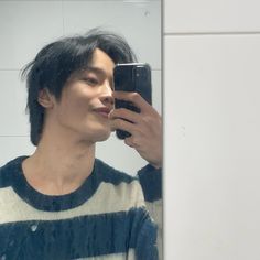 a young man taking a selfie in front of a mirror with his cell phone