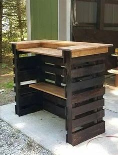 a wooden table made out of pallets on the side of a building in front of a garage