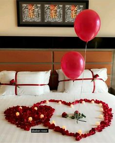 a heart shaped bed with two red balloons attached to the headboard and hearts made out of flowers