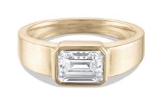 a yellow gold ring with an emerald cut diamond in the center, on a white background