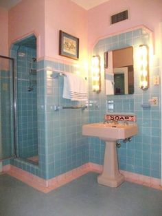 a bathroom with blue tiles and pink walls, including a pedestal sink in the corner