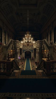 a large chandelier hanging from the ceiling in a dark room with stairs leading up to it