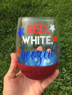 someone is holding up a wine glass with red, white and blue glitter on it