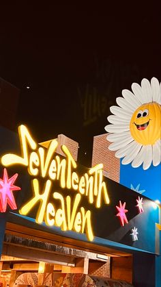 the neon sign for seventh heaven is lit up in front of a building with flowers on it