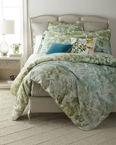 a bed with green and blue comforters in a bedroom next to a lamp on a nightstand