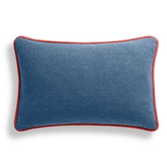 a blue pillow with red piping on the front and back, sitting on a white surface