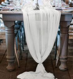 the table is set with white linens and place settings for an elegant dinner party