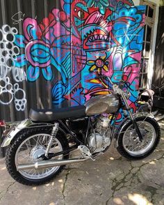 a motorcycle is parked in front of a wall with colorful graffiti on it's side