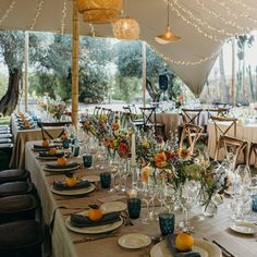 a table set up with place settings for an outdoor dinner party under a tented area