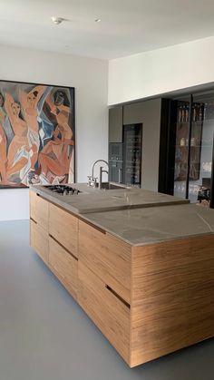 a modern kitchen with an island sink and large painting on the wall behind it's countertop