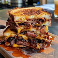 a stack of grilled sandwiches sitting on top of a cutting board next to a glass of beer