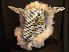 a white sheep mask with yellow eyes on a black background