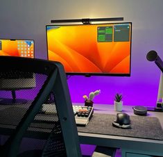 a computer desk with two monitors and a keyboard on it, in front of a purple wall